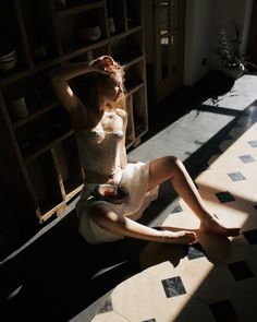 a woman sitting on the floor in front of a book shelf wearing a corset