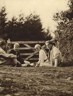 an old black and white photo of people sitting on the ground