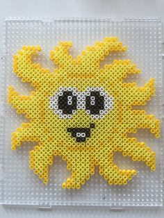 a yellow and black beaded sun on a white surface