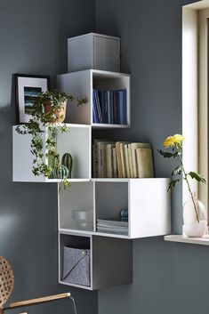 a white shelf filled with books next to a window and a vase full of flowers