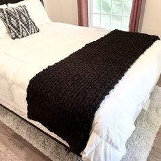 a bed with white and black blankets on top of it