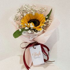 a bouquet of sunflowers and baby's breath tied to a white card