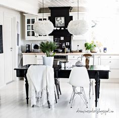 a black and white kitchen with chairs, table and lights hanging from the ceiling above it