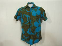 "Vintage 1960s op art Hawaiian shirt. Made of cotton. Color is electric blue and green/brown with hibiscus flowers like Warhol's poppies. Shirt has a button front, top button loop and single matching pattern chest pocket. Made by Hawaiian Casuals. Made in Hawaii. Size small. Measurements are: 39\" at the chest 39\" at the waist 15.5\" shoulder seam to shoulder seam 28\" overall length In very good condition." Green Retro Print Shirt For Spring, Retro Printed Hawaiian Shirt For Spring, Spring Retro Printed Hawaiian Shirt, Fitted Collared Hawaiian Shirt In Cotton, Retro Green Cotton Shirt, Fitted Cotton Collared Hawaiian Shirt, Green Retro Cotton Shirt, Fitted Graphic Print Hawaiian Shirt, Retro Fitted Hawaiian Shirt For Spring