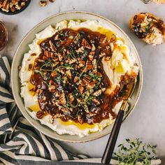 mashed potatoes topped with gravy and chopped pecans in a bowl next to other dishes