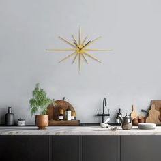 a kitchen counter topped with pots and pans under a yellow starburst clock