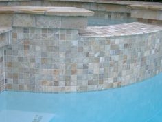 an empty swimming pool with tiled walls and steps