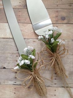 two forks with flowers tied to them sitting on a wooden table next to each other