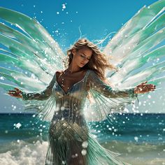 a woman in a green dress standing on the beach with her wings spread wide open