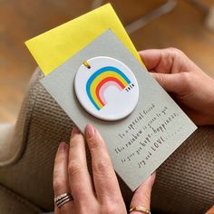 a woman holding a card with a rainbow on it and a note attached to it