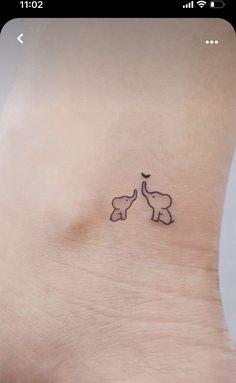 an elephant tattoo on the side of a woman's ankle, with two elephants touching their trunks