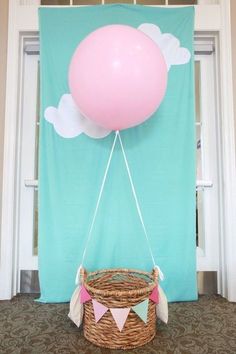 a pink balloon floating in the air over a basket