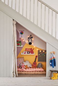 a child's bedroom under the stairs with toys and decor on display in it