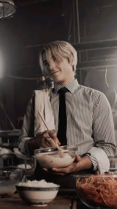 a man is holding a bowl with noodles in it while wearing a tie and looking at the camera