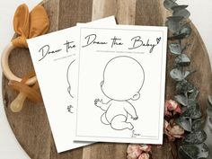 two baby's drawings sitting on top of a wooden table next to some flowers