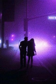 two people standing in front of purple lights