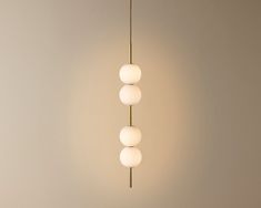 three white balls are hanging from a brass colored light fixture in a room with neutral walls