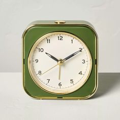 a green and white square clock with numbers on the face is sitting on a table