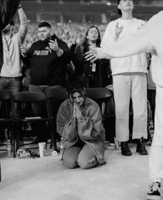 a person kneeling down in front of a crowd