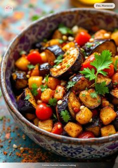 a bowl filled with eggplant, potatoes and tomatoes