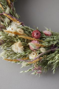 dried flowers and grass are arranged in a wreath