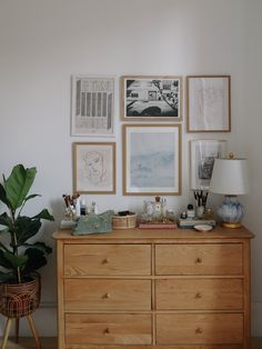 a wooden dresser sitting next to a wall covered in pictures and art on top of it