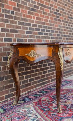 an antique wooden table sitting in front of a brick wall