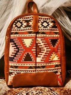 Indulge your wanderlust with our Handmade Bohemian Leather Rucksack, featuring a unique blend of kilim fabric and medium tan/brownish mustard leather. This exclusive design is perfect for all your adventures, whether you're a student, fashion enthusiast, or simply love to explore. Practical and Stylish: Our rucksack is the ideal companion for any journey. Whether you're strolling through city streets, hiking in nature, or commuting to work, this bag effortlessly combines style and functionality. Perfectly Sized: With measurements designed for convenience and comfort, our rucksack is the ideal medium size for all your needs. Its versatile design makes it perfect for a variety of activities and occasions. Expertly Handmade: Each rucksack is handmade with care, ensuring that each one is uniqu Artisan Backpack For Travel, Artisan Travel Backpack, Bohemian Leather Backpack For Everyday Use, Bohemian Leather Backpack With Adjustable Strap, Bohemian Leather Backpack For Everyday, Everyday Bohemian Leather Backpack, Bohemian Backpack For Everyday Use, Artisan Brown Backpack For Travel, Bohemian Leather Backpack With Adjustable Strap For Travel