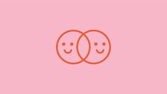 two oranges with faces drawn on them in the shape of hearts, against a pink background