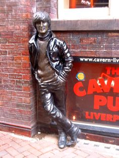 a statue of a man standing next to a brick wall