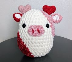 a crocheted pig with hearts on it's head sitting on a table