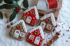 three decorated gingerbread houses next to a spool of twine and some red ribbon