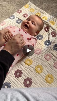 a woman holding a baby on top of a bed next to an adult's hand