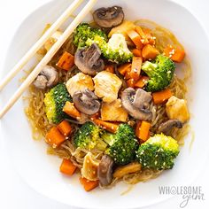 a white plate topped with broccoli, carrots and mushrooms next to chopsticks