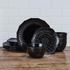 black dinnerware set on wooden table with white brick wall in the backround