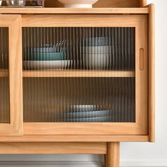 a wooden cabinet with glass doors and plates on it