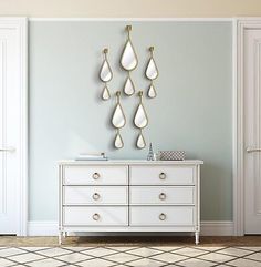 a white dresser sitting in front of a wall with hanging raindrops on it