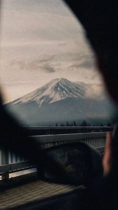 the view from inside a vehicle looking at a snow covered mountain in the back ground