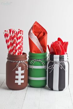 four mason jars filled with paper straws and candy canes, all decorated in different colors