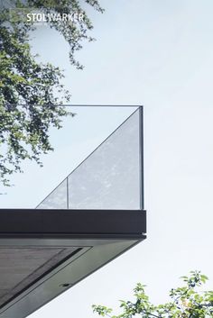 the top of a building with a glass railing on it's side and trees in the background