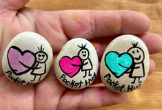 three painted rocks in the shape of children's hearts