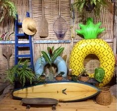 there are many tropical items on display in this room, including a surfboard and pineapple shaped planters