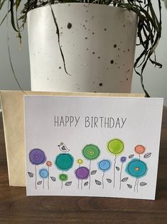 a happy birthday card with colorful flowers on it next to a potted green plant