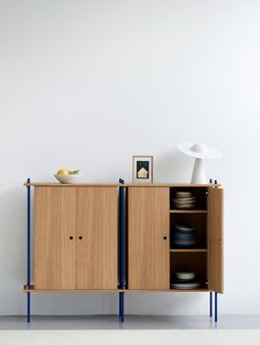 a wooden cabinet with two doors and some plates on the bottom shelf next to it