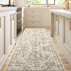 a kitchen with white cabinets and an area rug on the floor in front of a window