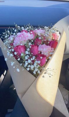 a bouquet of pink roses and white baby's breath sits in the passenger seat of a car