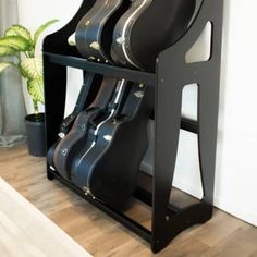 a black guitar case sitting on top of a wooden floor next to a potted plant