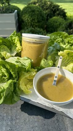 a bowl of soup next to some lettuce and a cup of peanut butter