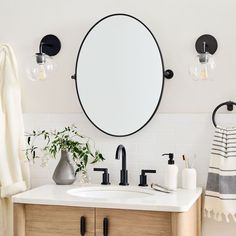 a bathroom sink with a round mirror above it