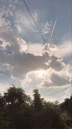 the sun is shining through some clouds in the sky above trees and power lines on a sunny day